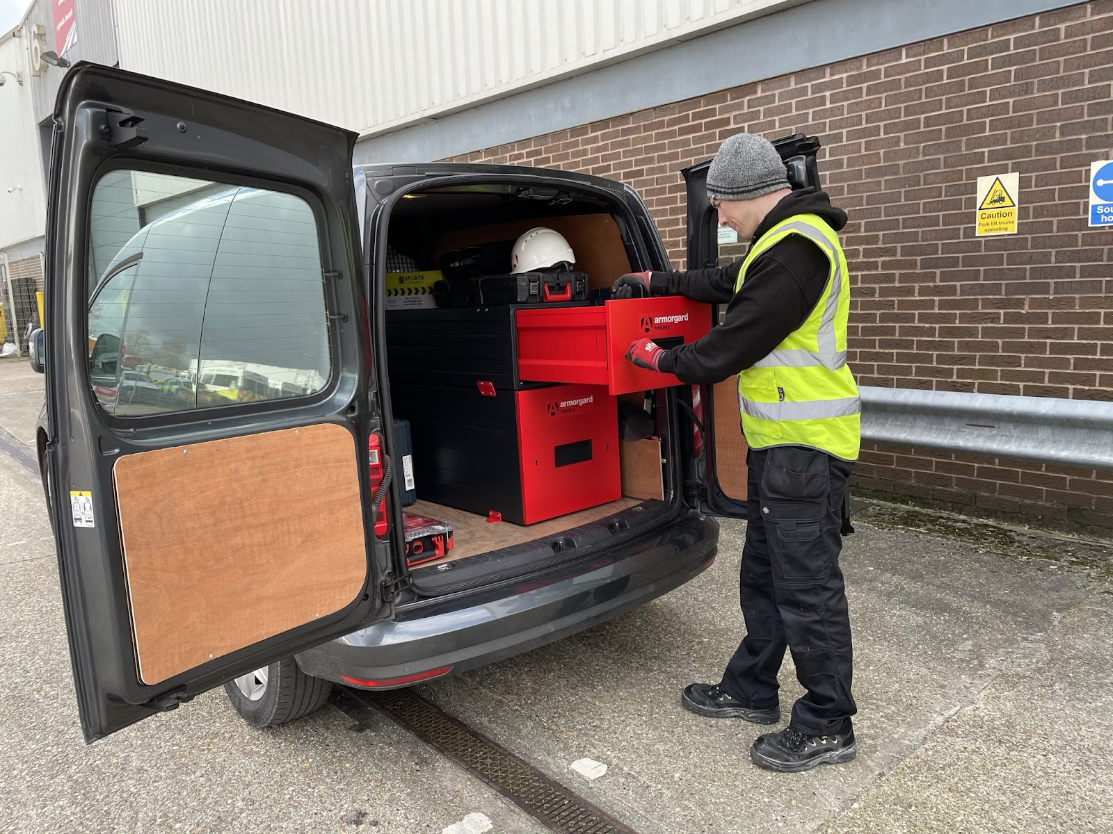 A person in a hi vis is taking equipment out of their TrekDror which is installed in the back of their van
