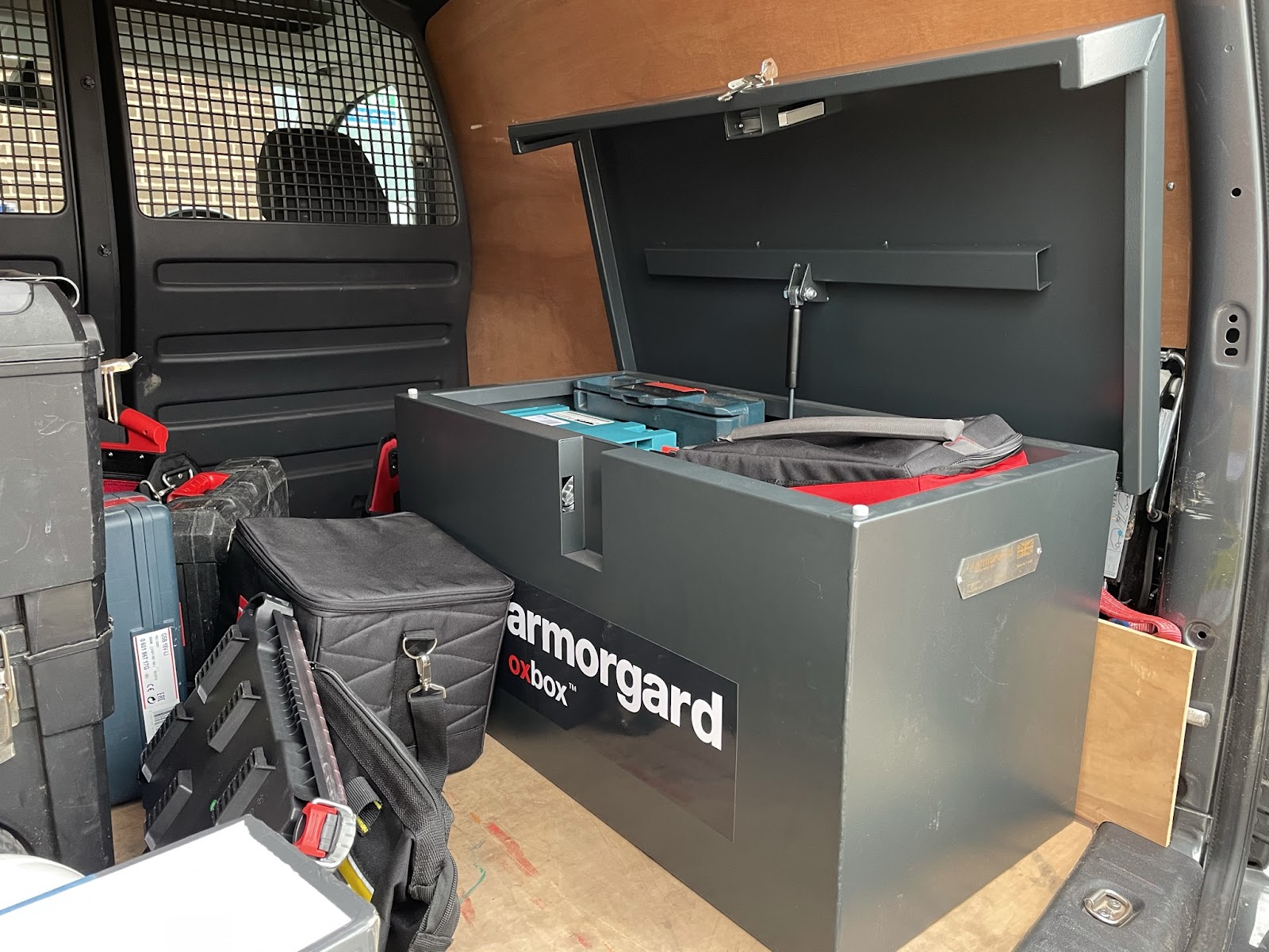 An Armorgard OxBox which is a tool chest with construction related objects inside of it located in the back of a van
