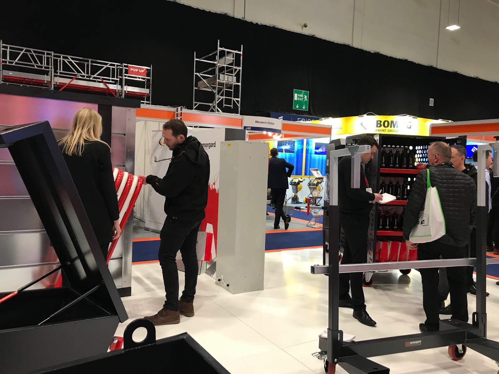 People standing and talking in the background and near them there are storage boxes and trollies from Armorgard around them