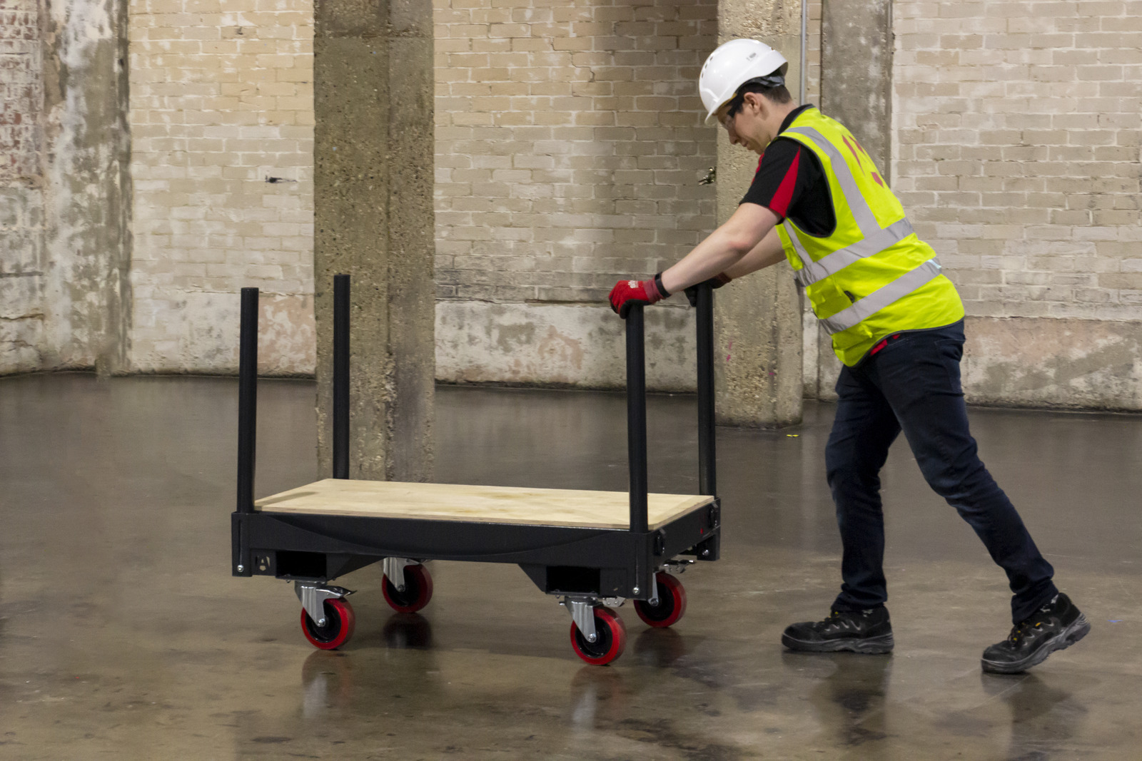 A man in a hi vis with a white helmet pushes a FlexiKart which is based on four swivel wheels