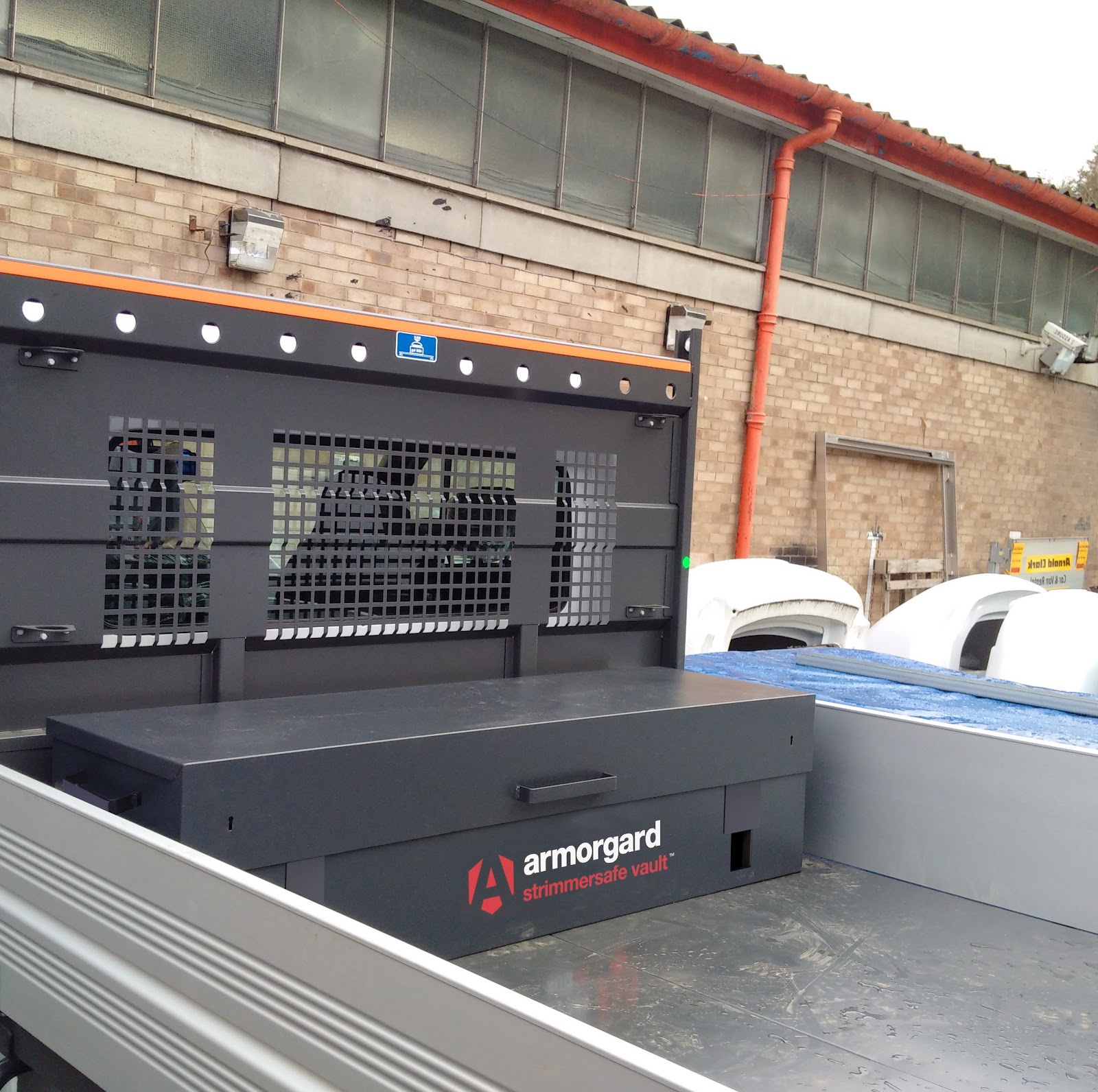 A black strimmersafe vault on the flatbed of a van with a building in the background