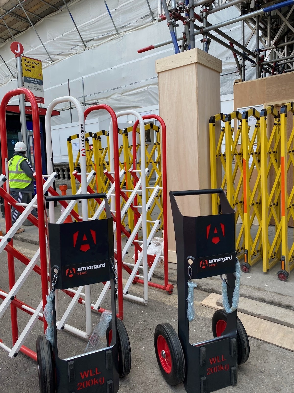 two Armorgard T-Karts side by side at a building site with scaffolding in the background