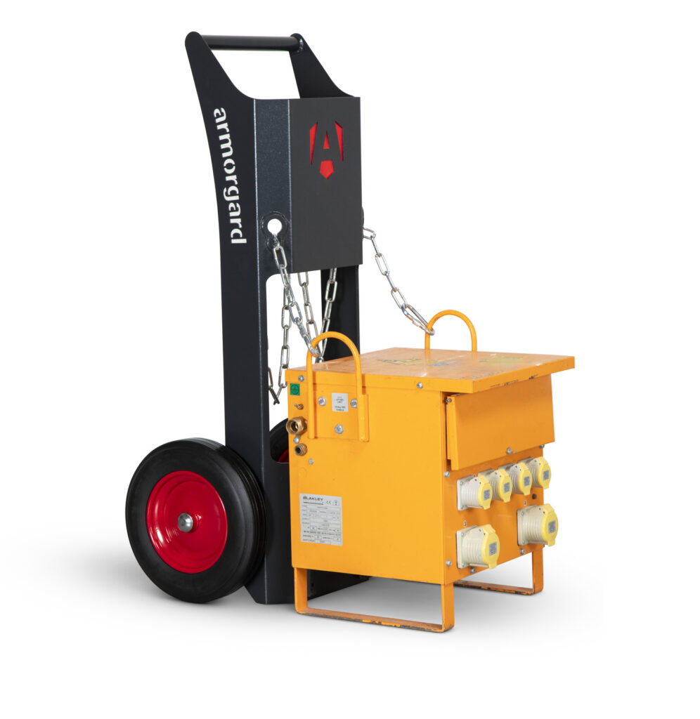 A black T-Kart with red wheels carrying a yellow 10 kVA site transformer, which is attached by chains to the T-Kart