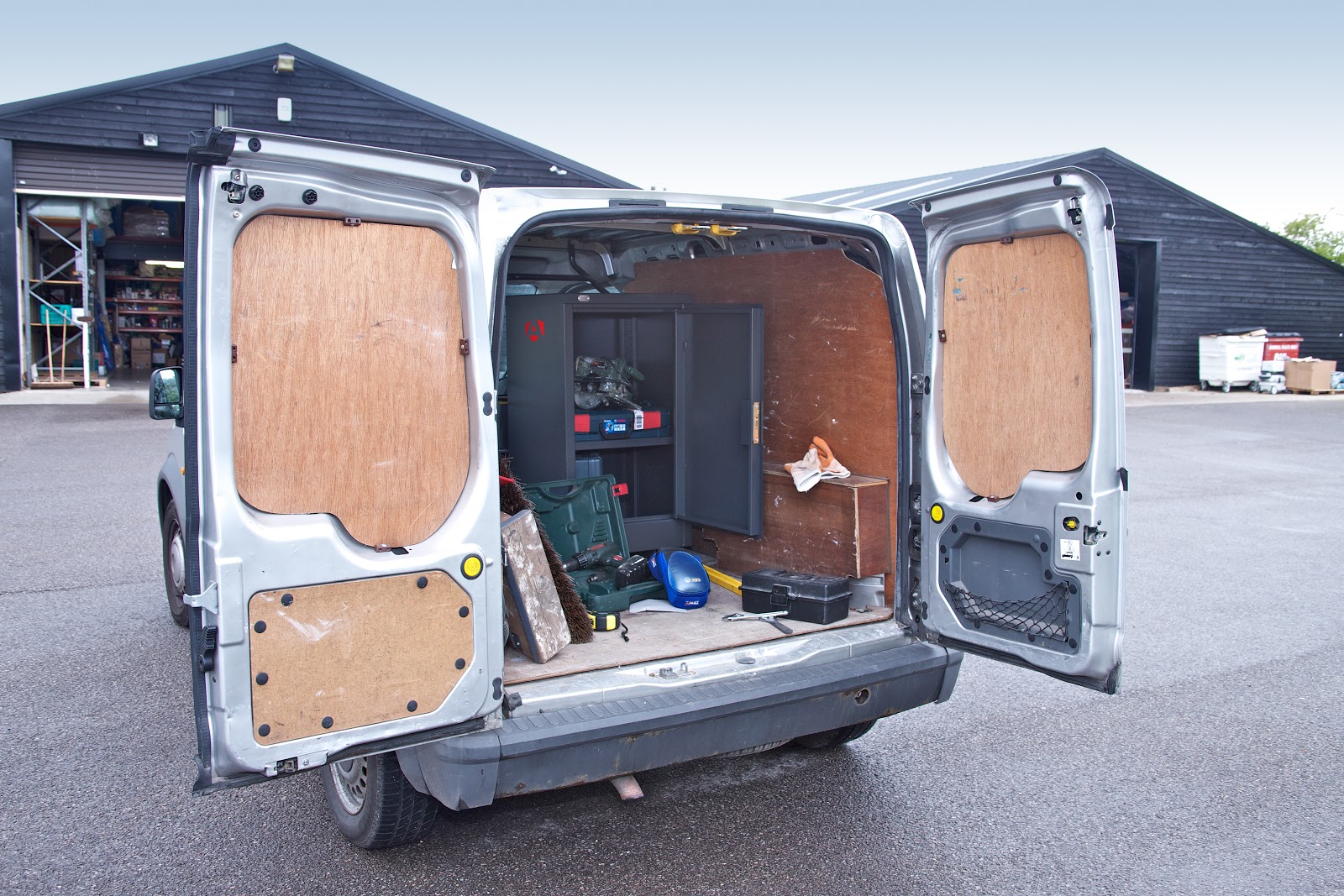 A van with its rear doors open showing some building site equipment and a black TuffStor Cabinet with its door open