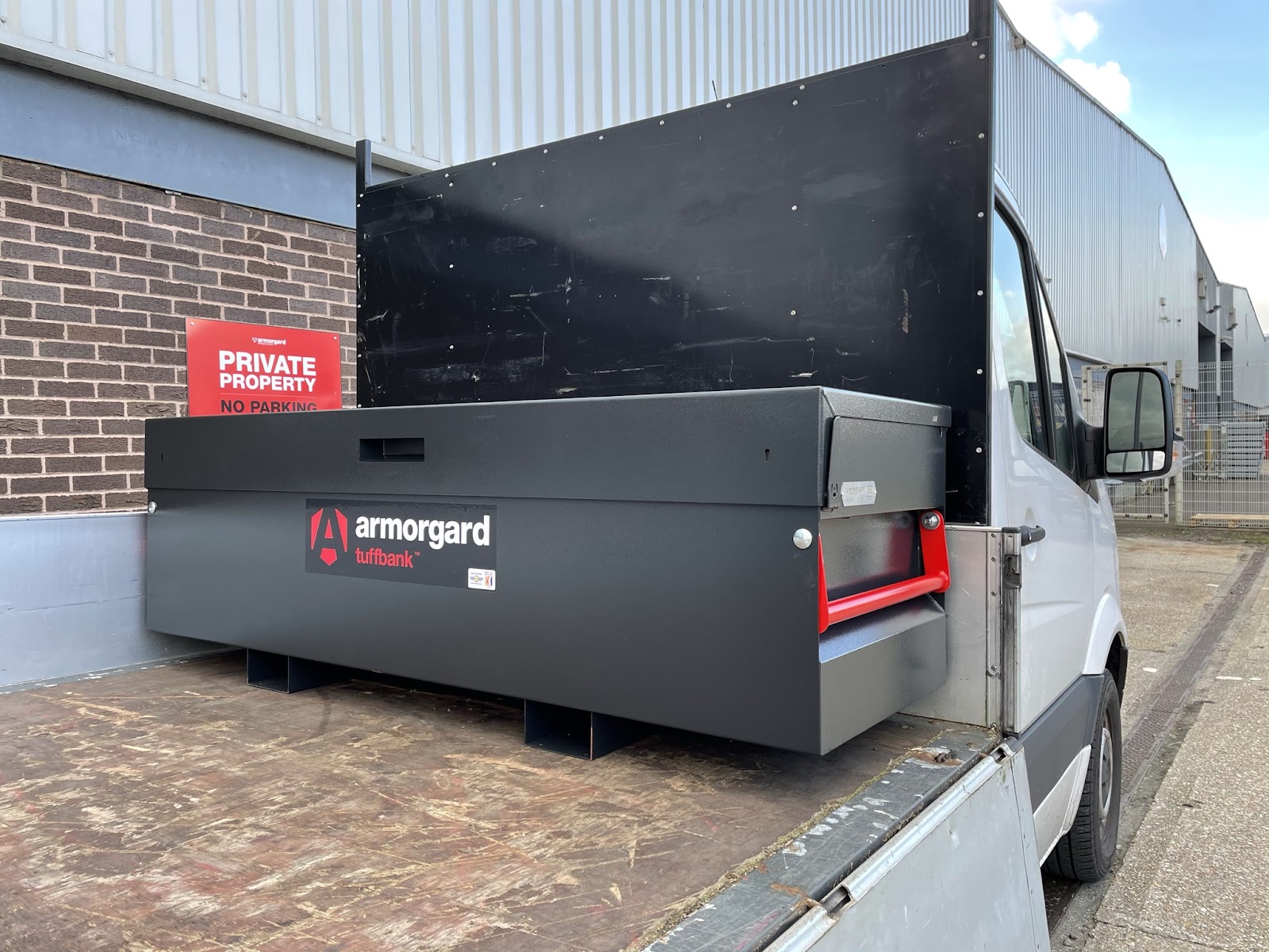 A black armorgard tuffbank storage container on a flatbed of a van