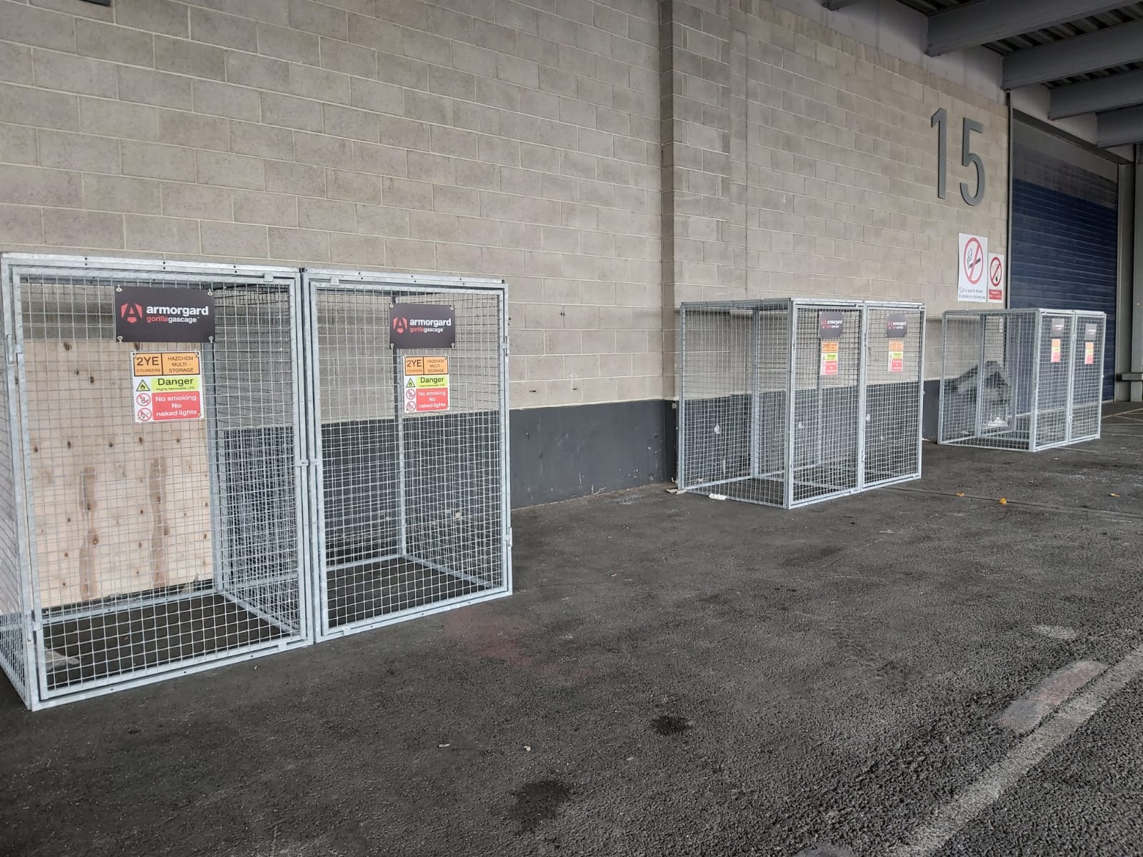 6 gorilla gas cages all lined up against the wall in pairs and the pairs are a bit spaced out, the cages are made of a fence like looking material.
