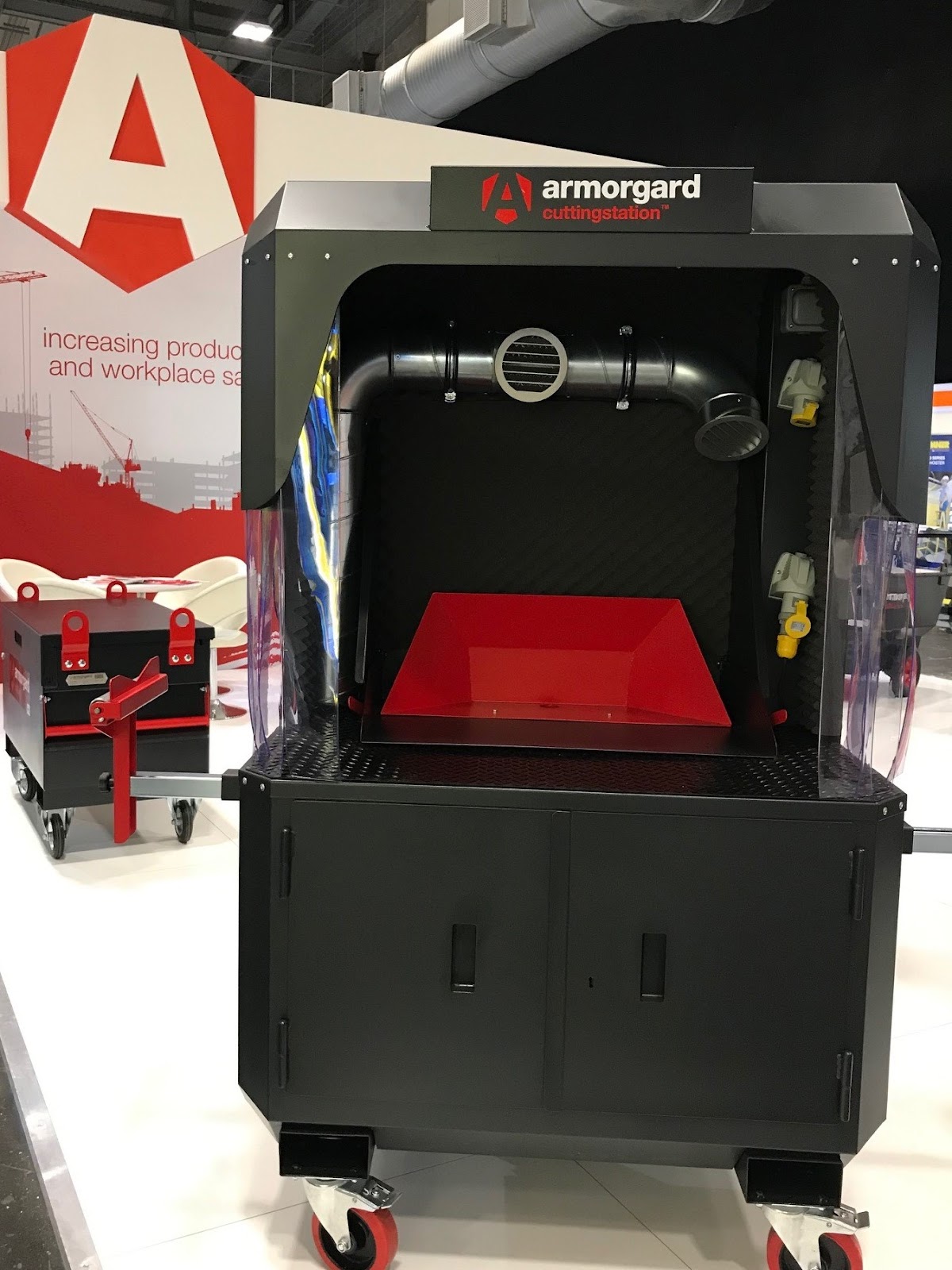 An Armorgard cutting station in black with red accents at the executive hire show. Near the top of the cutting station there is a SS7X extractor unit.