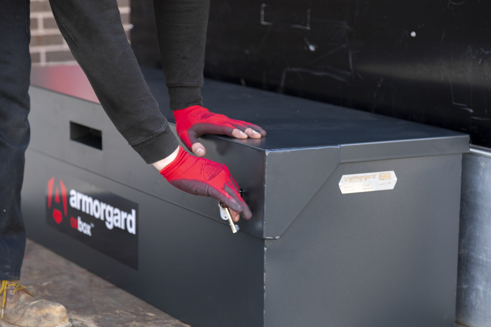 A person wearing gloves is using a key to unlock their tool chest called OxBox