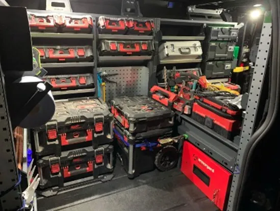 The inside of a van with a significant amount of tool boxes aswell as a TrekDor installed in the van on the floor