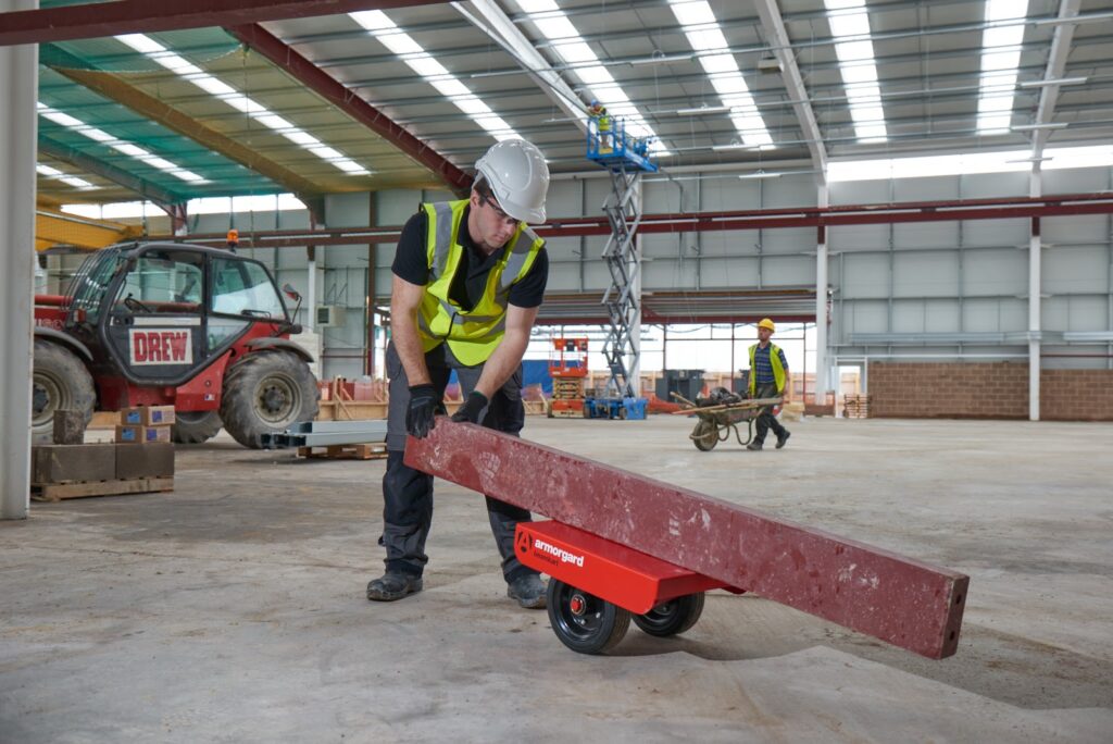 a man in a hi vis in a building site using a beam kart to move a beam
