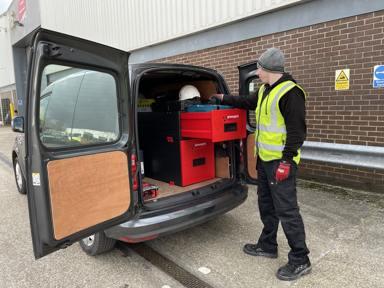 A person taking out a box of their tools from an Armorgard TrekDror which is in the back of the persons van
