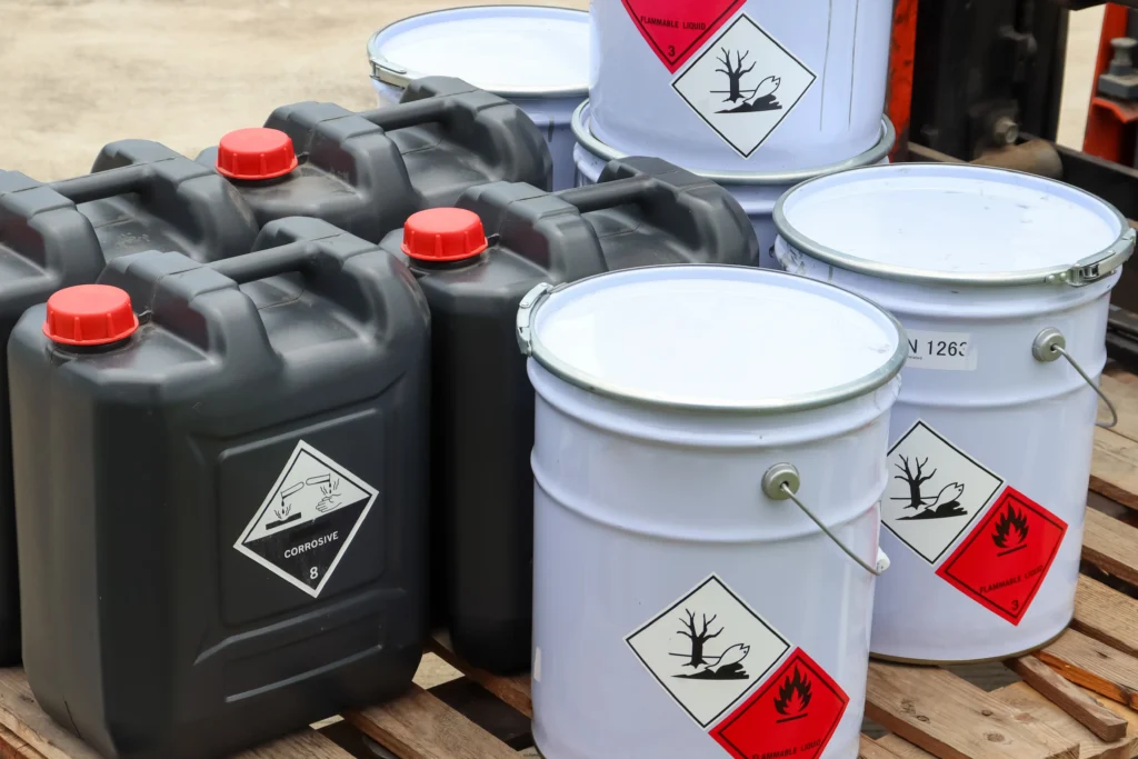 Chemical containers and drums labelled as flammable and corrosive, showing hazardous materials that require safe storage and guidance on how to dispose of hazardous waste correctly.