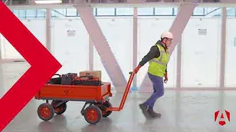 a person in a high vis is seen pulling a turntable truck with some equipment in it