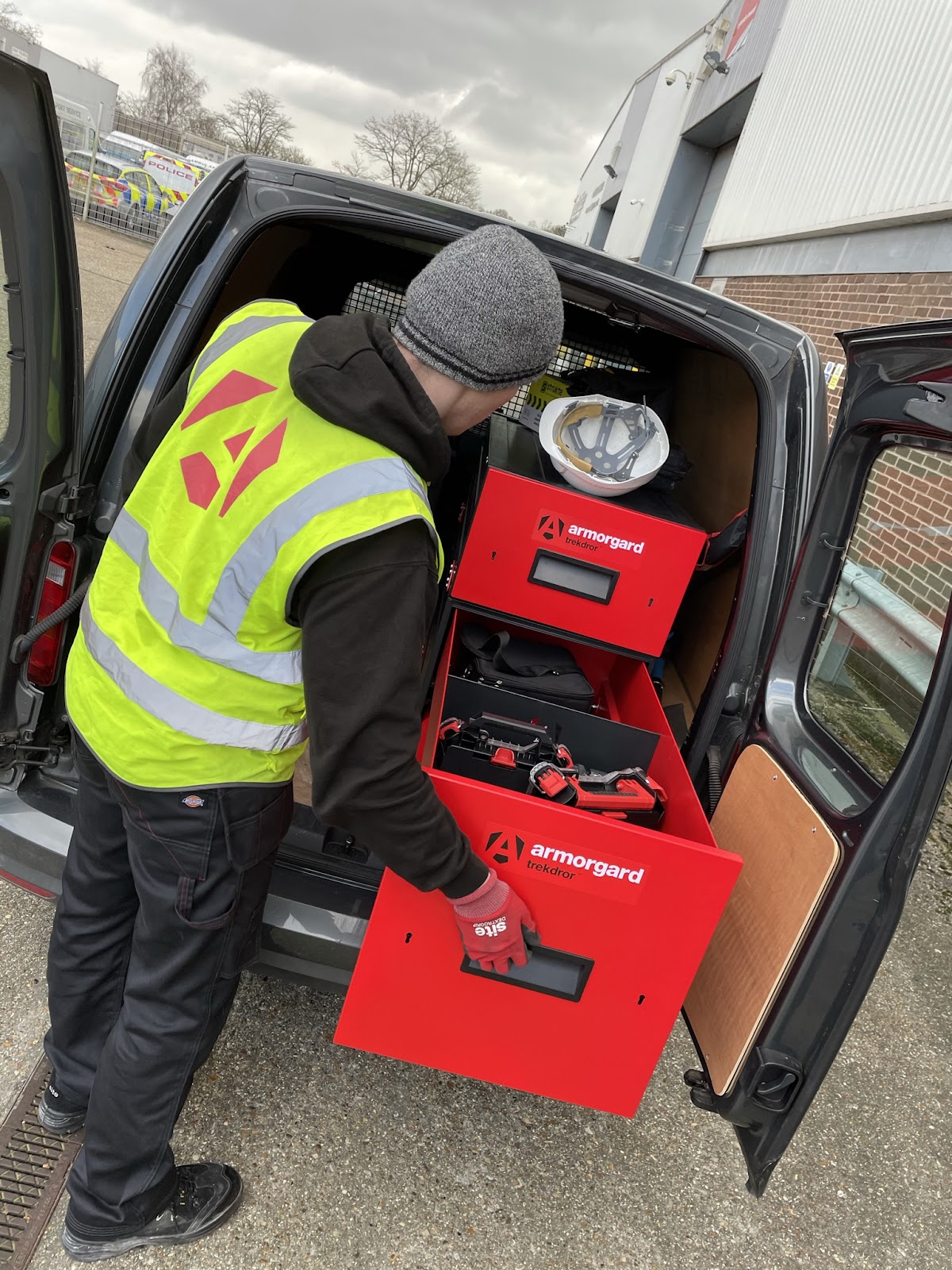 A person in a hi-vis vest opening up a draw from an Armorgard trekdror which is located in he back of a van
