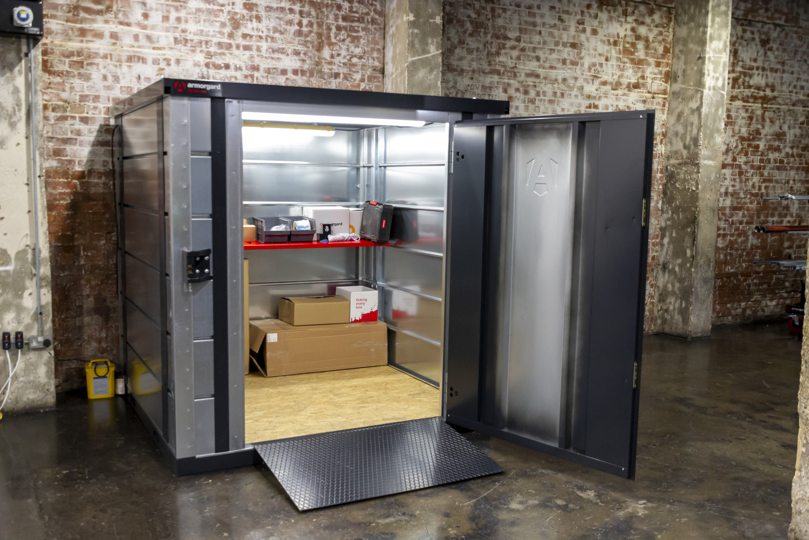 A walk-in storage unit with the door open showing some boxes and equipment inside