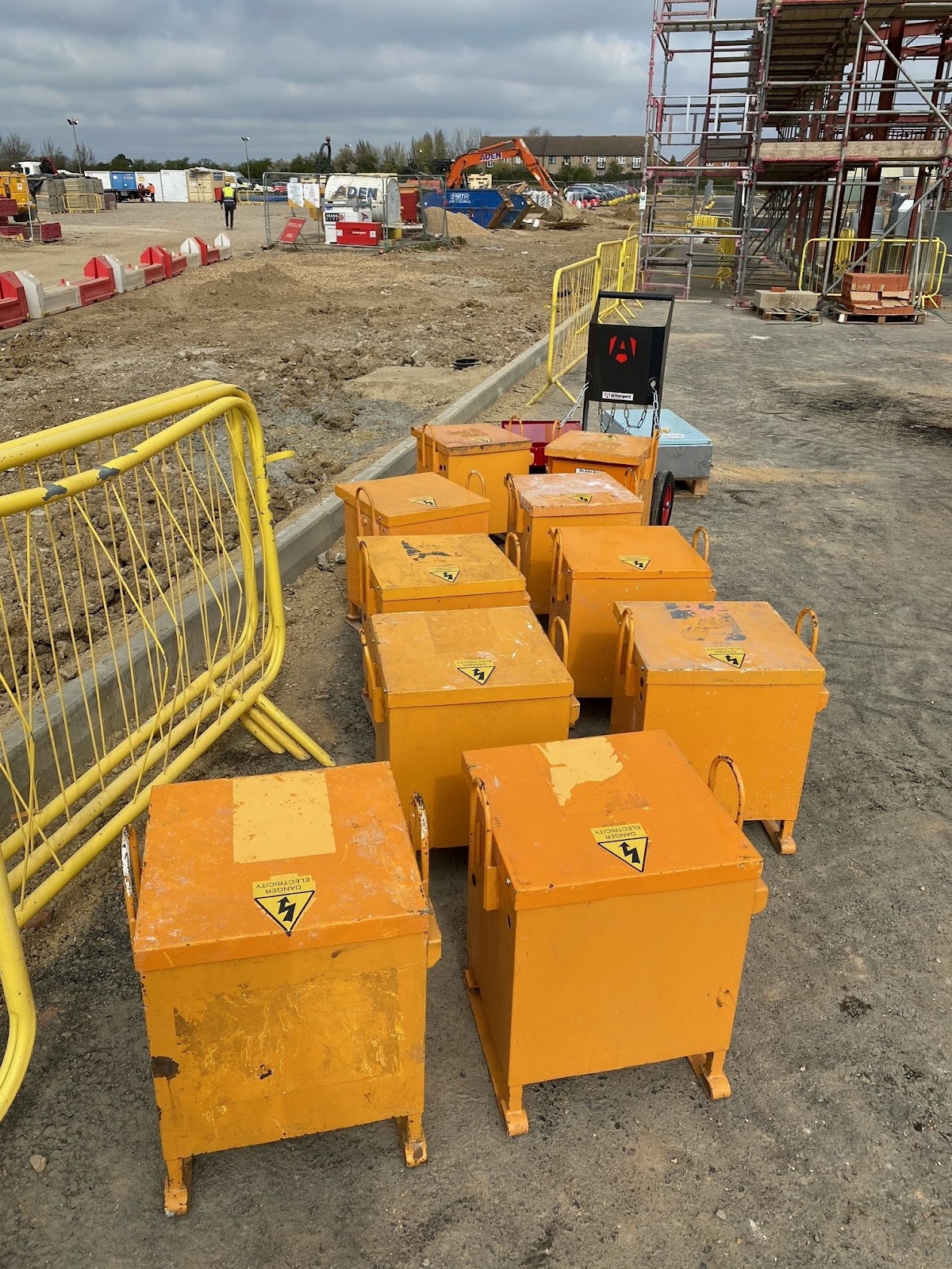 A group of 10 yellow site transformers at a building site with a T-Kart in the background