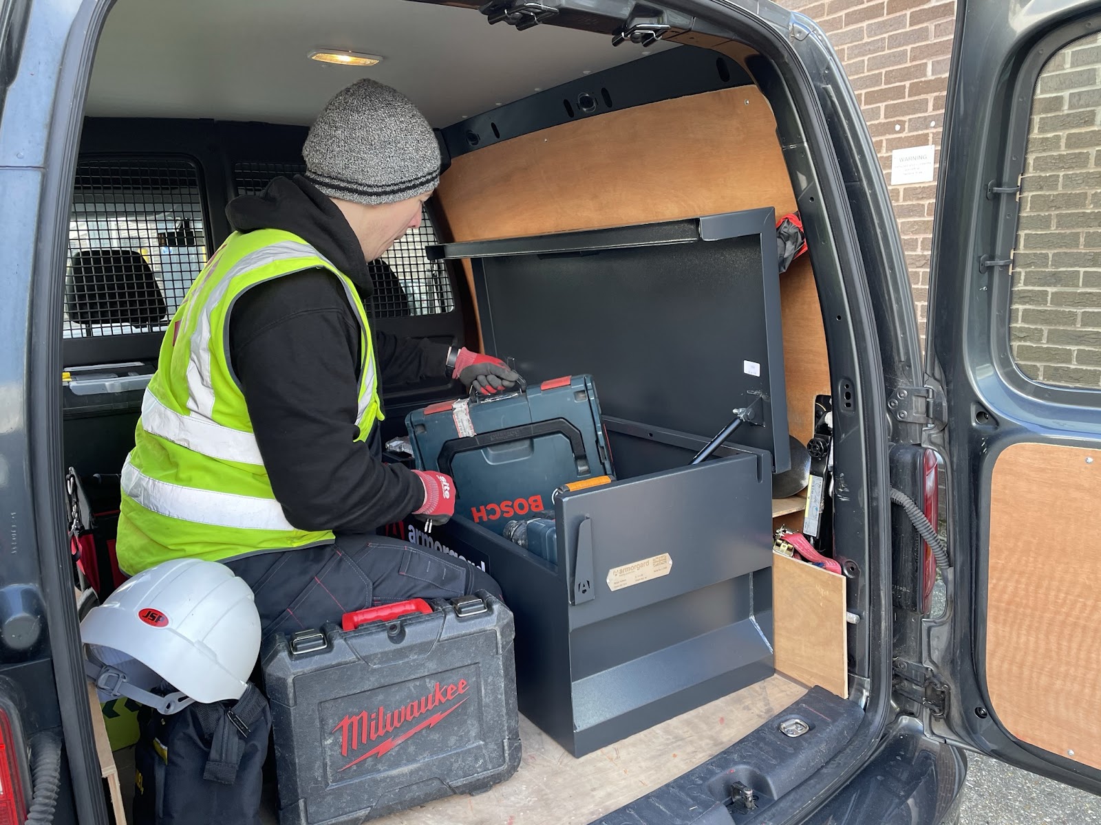 A person in a high vis is in the back of their van taking out or putting tools back into their TuffBank