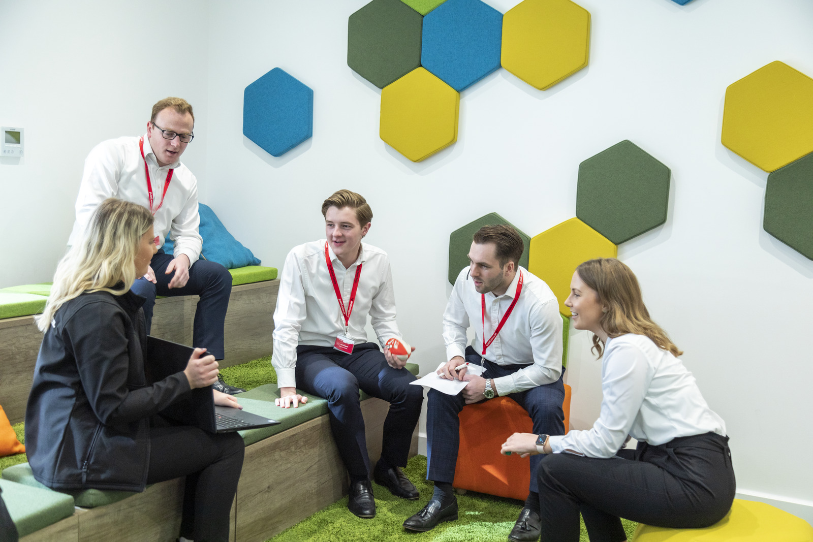 A group of 5 Armorgard employees talking and one person showing them something on their laptop screen